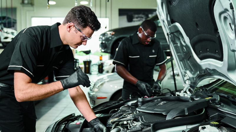 two automotive repair techs working on car